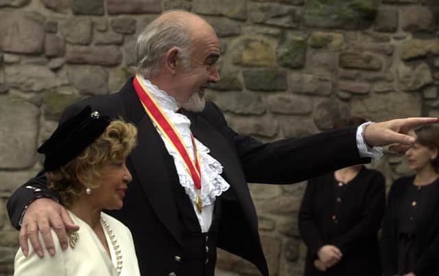 Sir Sean Connery  accompanied by his wife, Micheline points at someone in the crowd after receiving his Knighthood from HM The Queen at The Palace of Holyroodhouse. Pic Neil Hanna