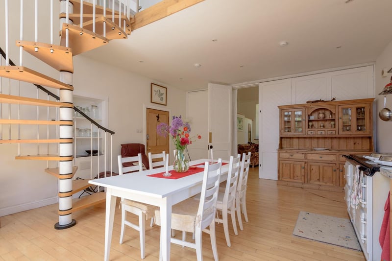 In the open plan kitchen-diner, a spiral staircase rises to a mezzanine area, off which is floored attic space.