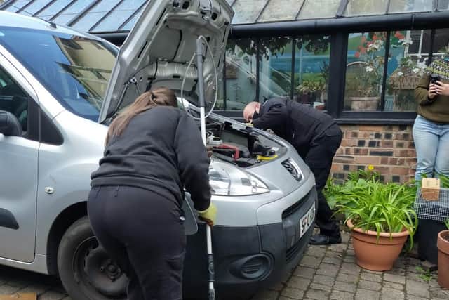 Animal rescue officers from the Scottish SPCA try to coax the otter out from under the car.