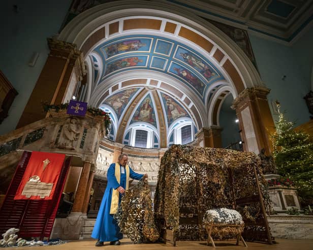 St Cuthbert's minister Rev Peter Sutton with the nativity scene featuring camouflage nets made by Ukrainian refugees in the Edinburgh Spiders group. Picture: Jane Barlow/PA Wire.