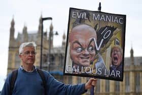 A demonstrator holds a placard showing Boris Johnson and his former special adviser Dominic Cummings outside the UK Parliament (Picture: Justin Tallis/AFP via Getty Images)