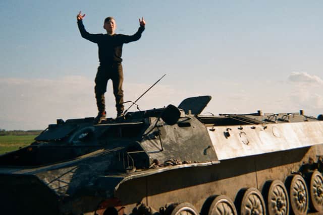 One boy stands on an abandoned tank after Russian forces withdrew from his village