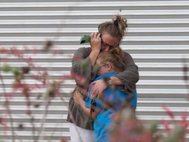 A woman cries and hugs a young girl while on the phone outside the Willie de Leon Civic Center where grief counseling will be offered in Uvalde, Texas, on May 24, 2022. 
The attack in Uvalde, Texas -- a small community about an hour from the Mexican border -- is the latest in a spree of deadly shootings in America, where horror at the cycle of gun violence has failed to spur action to end it. (Photo by Allison dinner via Getty Images)