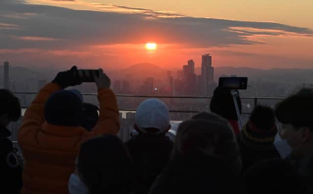 People enjoy the last sunset of the year on a viewing deck at Namsan tower in Seoul on December 31, 2020.