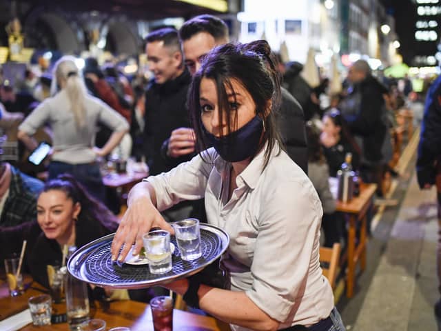A waitress serves drinks at tables outside a pub in Soho, London, on the day some of England's coronavirus lockdown restrictions were eased (Picture: Alberto Pezzali/AP)