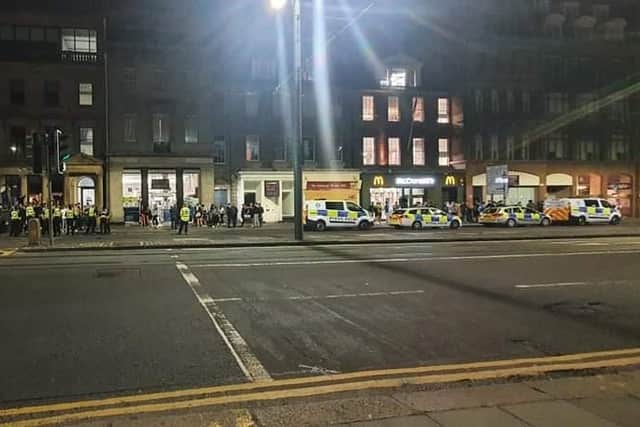 Two police vans and two police cars can be seen parked on Princes Street as officers approach fans (Photo: William Scally).