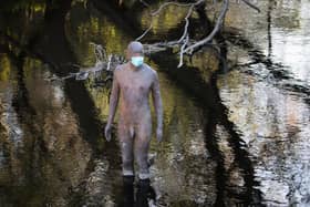 One of artist Antony Gormley's "6 TIMES" statues in the Water of Leith, Edinburgh, wears a protective face mask as the UK continues in lockdown to help curb the spread of the coronavirus.