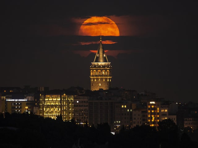 The moon reached its full stage on Tuesday, as pictured here behind the Galata Tower in Istanbul, Turkey, (AP Photo/Emrah Gurel)
