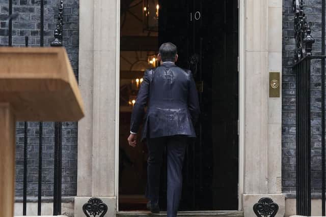 Prime Minister Rishi Sunak, soaked by rain, walks back in to 10 Downing Street after calling a general election for July 4