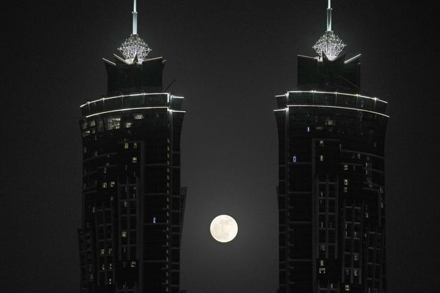 The full moon rises between two towers, in Dubai, United Arab Emirates, Tuesday, June 14, 2022. (AP Photo/Kamran Jebreili)