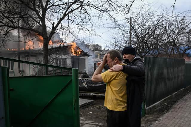 Yevghen Zbormyrsky, 49, is comforted as he stands in front of his burning home after it was shelled in Irpin, outside Kyiv (Picture: Aris Messinis/AFP via Getty Images)