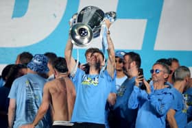 Manchester City's John Stones celebrates on stage with the Champions League Trophy during the Treble Parade in Manchester earlier this month (Picture: Nigel French/PA)