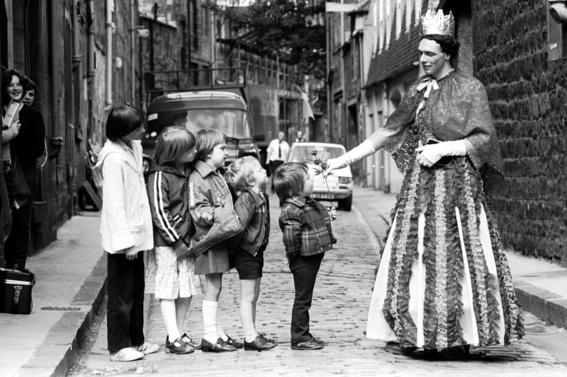 One of the performers from the Edinburgh Festival Fringe production of Rumpelstiltskin presents a rose to some children in August 1980.