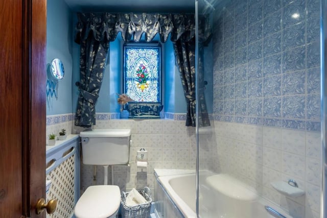 A stained glass window is an eye-catching feature of this room which contains a shower over the bath.