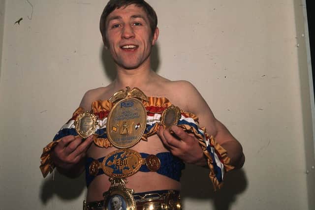 Ken holding a collection of boxing belts including Lonsdale Belt and World Title belt.