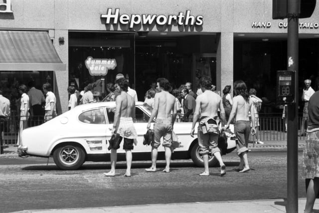 Four teenagers stripped to the waist and in bare feet crossing Princes Street by Hepworths during the long hot summer of 1976.