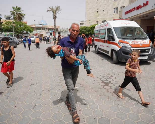 A man rushes Palestinian boy Khaled Abu Samaha to the Al-Aqsa Martyrs Hospital in the central Gaza Strip after he was injured in Israeli bombardment on a house in Nuseirat city on May 27 amid continuing battles between Israel and the Palestinian Hamas militant group (Photo by Bashar TALEB/AFP via Getty Images)