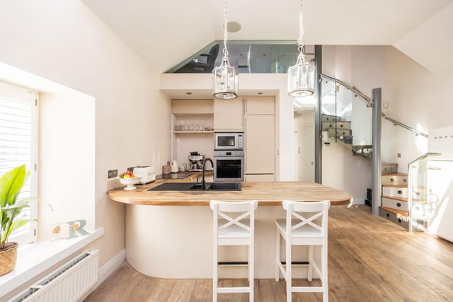 The fully-fitted modern kitchen space comes with a range of integrated white goods and breakfast bar.