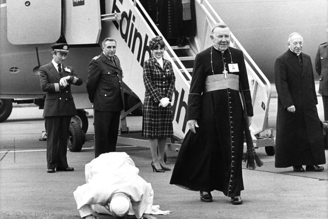 Pope John Paul II does his traditional kissing of the tarmac when he lands at Turnhouse Airport as Cardinal Gray looks on.