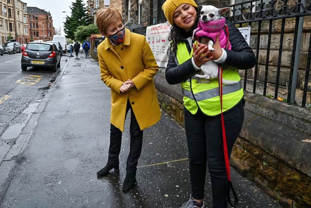 Nicola Sturgeon and candidate Roza Salih greet a dog as they arrive to cast votes in the Scottish Parliamentary election