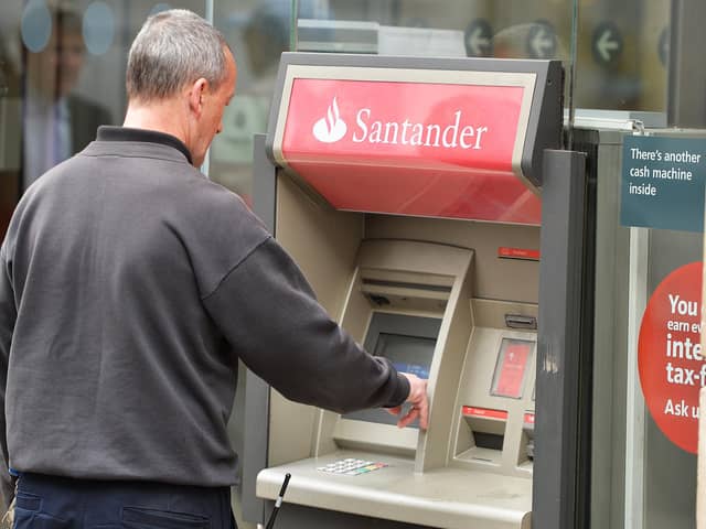 A man using a cash machine outside a branch of Santander in central London. Santander has announced it will be permanently closing 111 branches in the UK picture: John Stillwell/PA