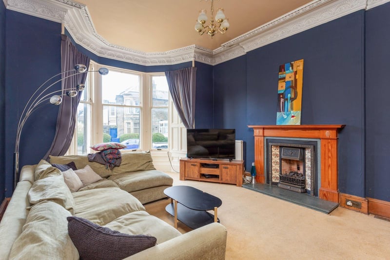 The bright and spacious west-facing living room with bay window, feature fireplace, Edinburgh Press and ornate cornicing.