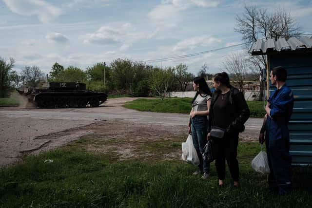 People watch a Ukrainian tank driving on a road after receiving packages from a food distribution in Rai-Oleksandrivka, eastern Ukraine, on April 29, 2022, amid Russia's military invasion launched on Ukraine. (Photo by Yasuyoshi CHIBA / AFP) (Photo by YASUYOSHI CHIBA/AFP via Getty Images)
