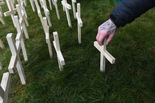 A man leaves a cross for his brother at a memorial for drug-death victims (Picture: John Devlin)