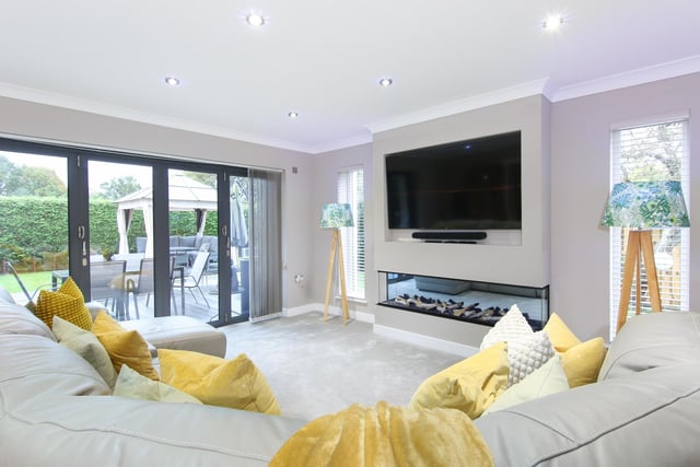 The contemporary living room, complete with a lovely electric fireplace and media wall, as well as a set of bi-fold doors leading to the garden.