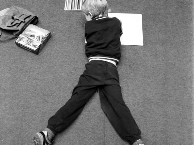 A little boy stretches out on the carpet at the annual Children's Art Competition held in the Royal Museum of Scotland in Edinburgh. Picture taken December 1988.