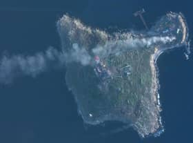 This satellite image taken by Planet Labs PBC shows smoke rising after Ukrainian strikes destroyed buildings housing Russian positions and a helicopter on Snake Island in the Black Sea Sunday, May 8, 2022. (Planet Labs PBC via AP)