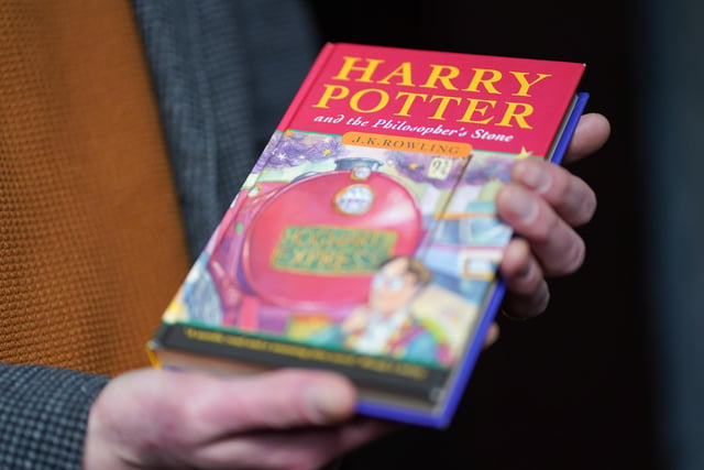 Auctioneer Jim Spencer holds a pristine first edition hardback of JK Rowling's Harry Potter and the Philosopher's Stone, one of only 500 produced in the first print run in 1997 22.