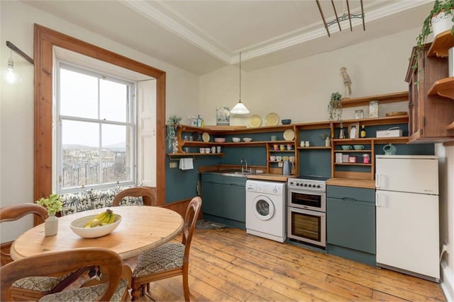 The kitchen has bespoke wooden shelving and maintains the original features including stripped floorboards and large sash and casement window with shutters.