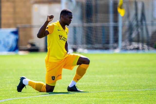 Livingston midfielder Marvin Bartley supports football's anti-racism movement by taking a knee ahead of a match this season. Photo by Ross MacDonald / SNS Group