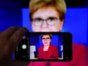 A person uses their phone to film a televised broadcast of First Minister Nicola Sturgeon. Picture: PA
