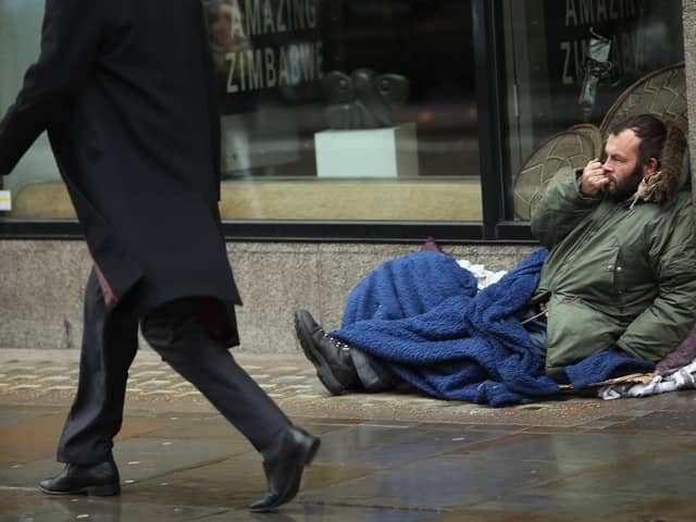A member of the public walks past a homeless man