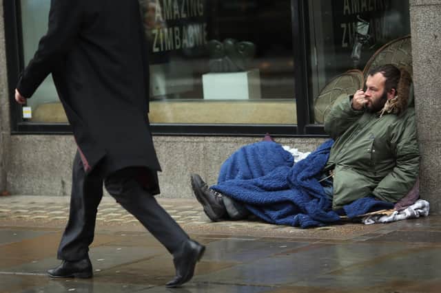 A member of the public walks past a homeless man