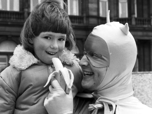 Carol Mitchell (6) gets a banana from Bananaman during a banana promotion by the Banana Group in Edinburgh in May 1985.