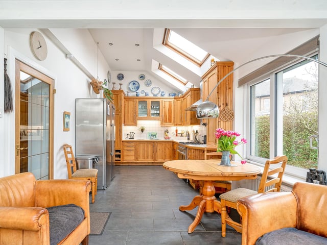 Kitchen with bespoke wall and floor units, tiled worktops and splashbacks, and a double oven stainless steel range cooker with extractor hood. A generous utility room adjoins the kitchen and offers a seamless flow into the dining room.