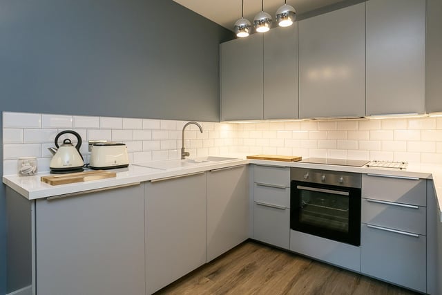 Modern units and worktops include a tiled surround, a sink with drainer; an integrated oven, induction hob and dishwasher, and a freestanding fridge/freezer.