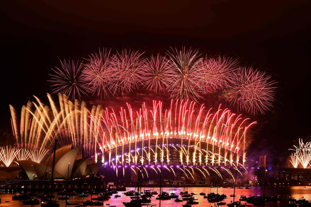 New Year's Eve fireworks erupt over Sydney's iconic Harbour Bridge and Opera House (L) during the fireworks show on January 1, 2021.