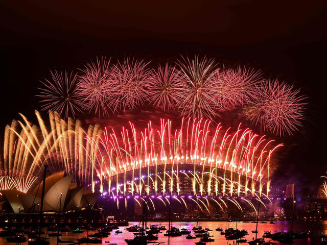 New Year's Eve fireworks erupt over Sydney's iconic Harbour Bridge and Opera House (L) during the fireworks show on January 1, 2021.
