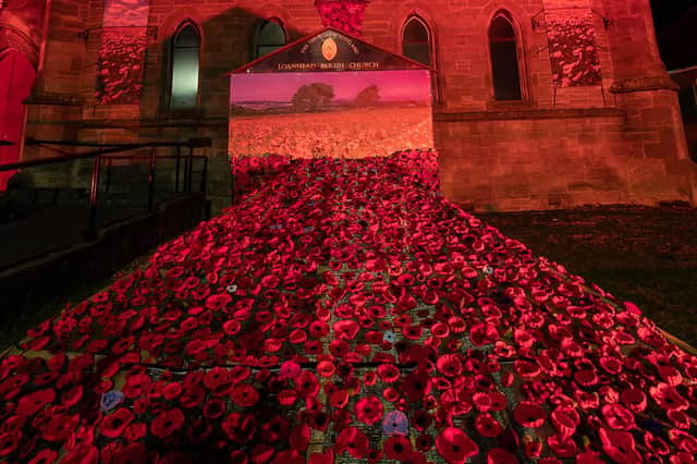 Loanhead Parish Church lit up red for Remembrance, with poppy-filled garden of remembrance.  Photo by Joe Gilhooley.
