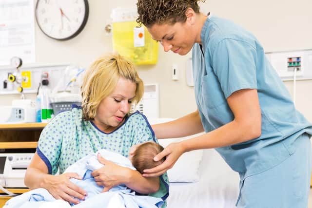 Midwife helping woman in holding newborn baby