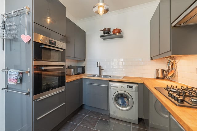 The well-laid out first floor kitchen features sleek grey cabinetry to off-set the white splashback and quality wooden worktops. Integrated appliances include an eye level double oven, extractor hood, and gas hob.