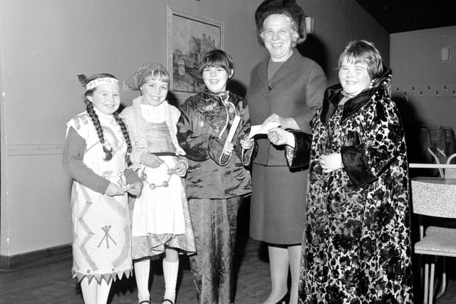 Guisers hand over money to Margaret Bayne, Convener of Lamb's House in Leith, in 1967.