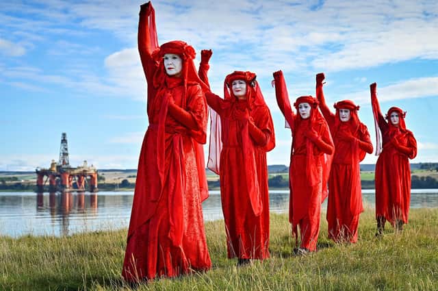 INVERGORDON, SCOTLAND - OCTOBER 06: Red robed protesters from Extinction Rebellion take part in blockading the oil rig maintenance facility at Cromarty Firth Port Authority on October 6, 2021 in Invergordon, Scotland. The group are calling for an end of fossil fuel extraction and support for a transition of skilled oil and gas workers into decommissioning and renewable industries, not new oil fields. (Photo by Jeff J Mitchell/Getty Images) *** BESTPIX ***