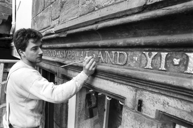 A workman repairs the gilded writing outside 16th century Moubray House in the High Street Edinburgh. When the picture was taken (December 1987), it was the oldest inhabited private house in Edinburgh.