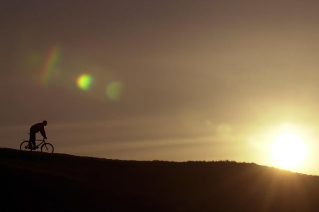 A cyclist makes his way along the top of Salisbury Crags at sunset.