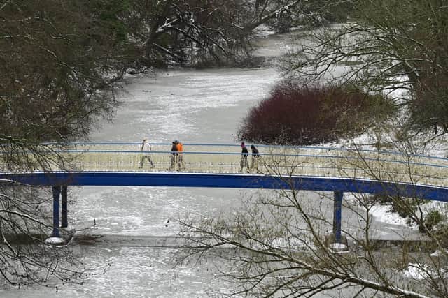 Walkers crossing Ha'penny Bridge over a frozen River Kelvin in Glasgow on Friday. Picture: John Devlin